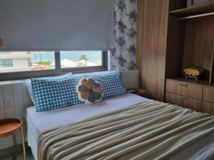 a bedroom with a bed with blue pillows and a window at PLAGE DU PORTO 204- Beira mar, centrinho turístico in Porto De Galinhas