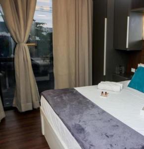 a bedroom with a bed and a window with a bathroom at Pousada do Braga in Cabo Frio