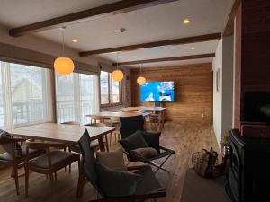 a dining room with tables and chairs and a tv at SLOPE in Kutchan