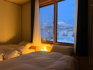 a bedroom with a bed and a large window at SLOPE in Kutchan