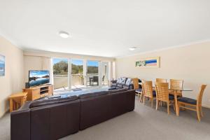 un salon avec un canapé, une table et une télévision dans l'établissement 11 Seashells, à Nelson Bay