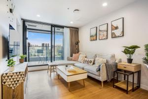 a living room with a couch and a table at Cosy Two Bedroom Apartment with Balcony Pool and Gym in Auckland
