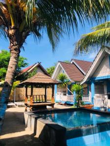 a house with a palm tree and a swimming pool at Youpy Bungalows in Gili Air