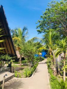 een pad door een tuin met palmbomen en een gebouw bij Youpy Bungalows in Gili Air