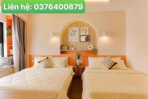 two beds in a hotel room with a sign that readslinear he at FLC Sea Tower Qui Nhơn Apartment - Căn Hộ Sea View in Quy Nhon