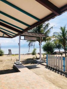 龍目島的住宿－Youpy Bungalows，海滩上的凉亭,带有栅栏和海洋