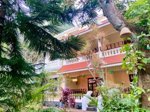 a house with a palm tree in front of it at Mango Villa in Varkala