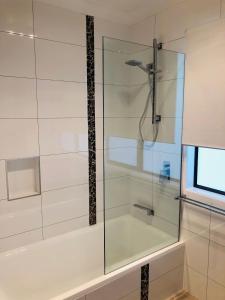 a shower with a glass door next to a tub at Rainbow Stairs in Rainbow Beach