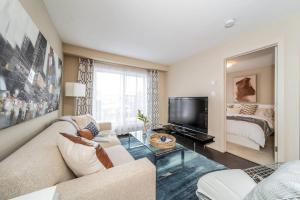 a living room with a couch and a television at Trendy Windermere Condo, AirCon, Top Floor, King Bed, Secure UG Parking, BBQ! in Edmonton