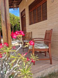 een veranda met 2 stoelen en bloemen bij Pousada Rio Aratuá in Galinhos