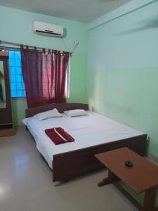 Bett in einem Zimmer mit einem Tisch daneben in der Unterkunft Goroomgo Star Inn Digha Near Sea Beach - Lift & Parking Facilities - Best Seller in Digha