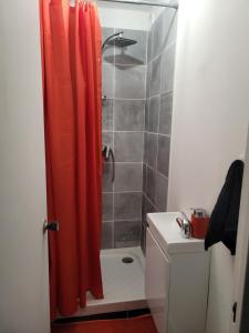 y baño con ducha y cortina de ducha de color naranja. en Le 9ème étage du bonheur, en Pointe-à-Pitre