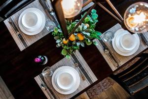 een houten tafel met witte borden en een vaas met sinaasappels bij Bright Luxe Condo, AC, Top Floor, King Bed, Balcony! in Edmonton