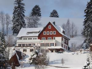 una grande casa rossa e bianca nella neve di Haus Sommerberg a Feldberg