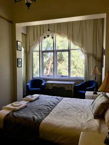 a bedroom with a bed and a large window at Toorak Manor Hotel in Melbourne