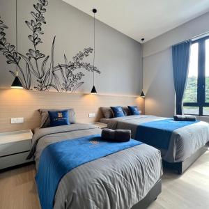 two beds in a room with blue sheets at Hotel Brynton at Centrum in Cameron Highlands