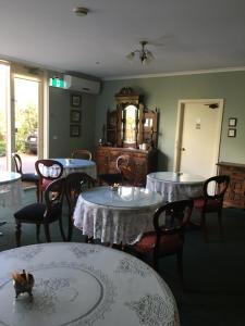 una sala da pranzo con tavoli, sedie e orologio di Toorak Manor Hotel a Melbourne