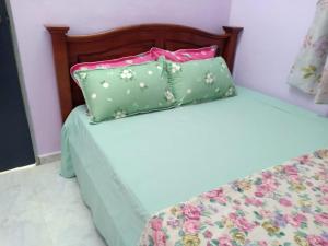 two beds with green and pink pillows on them at Inap Desa 2 in Baling