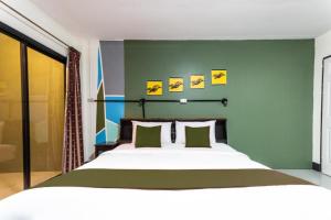 a bedroom with a large bed with green walls at Riverside Guesthouse in Khao Lak