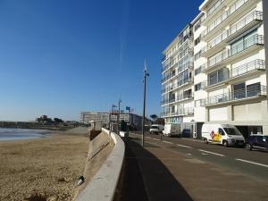 einen Bürgersteig neben einem Strand neben einem Gebäude in der Unterkunft T3 face plage avec balcon et parking, aux Sables-d'Olonne - FR-1-92-808 in Les Sables-dʼOlonne + 7 Fotos