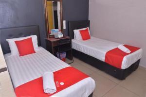 una camera d'albergo con due letti con cuscini rossi e bianchi di NICE STAY HOTEL a Raub