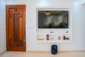 a room with a door and a television on a wall at Luxury, cozy apartment Alma Rosa /15 min airport in Los Tres Ojos de Agua