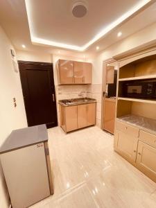 eine kleine Küche mit Holzschränken und einem Kühlschrank in der Unterkunft El mansour hotel apartmen 94 in Mansoura