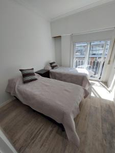 2 camas en una habitación blanca con ventana en Casa en Mar del Plata en Mar del Plata