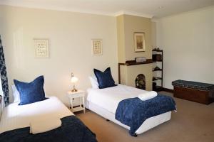 um quarto com 2 camas com almofadas azuis e uma lareira em Robin Hill Manor em Moss Vale
