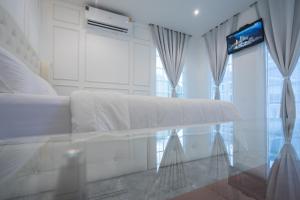 a white bedroom with a bed and a glass table at Je t'aime cafe & villa in Sing Buri