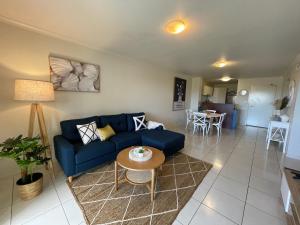 a living room with a blue couch and a table at City Stadium Apartment on the Riverfront 38 in Townsville