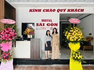 two women standing in front of a building with flowers at Sai Gon Motel in Da Nang