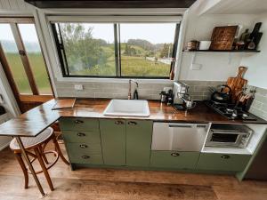 eine Küche mit einem Waschbecken und einer Theke mit einem Fenster in der Unterkunft Shepherd & Sprout Boutique Tiny House - Cradle Country in Wilmot