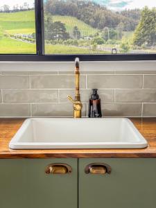 a white sink in a kitchen with a window at Shepherd & Sprout Boutique Tiny House - Cradle Country in Wilmot