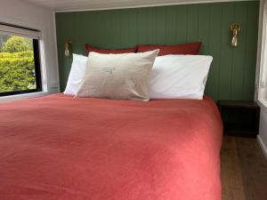 1 cama con manta roja y almohadas blancas en Shepherd & Sprout Boutique Tiny House - Cradle Country, en Wilmot