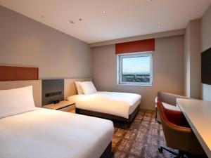 ein Hotelzimmer mit 2 Betten und einem Schreibtisch in der Unterkunft ANA Crowne Plaza Akita, an IHG Hotel in Akita