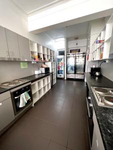 a large kitchen with white cabinets and appliances at The Downing Hostel in Sydney