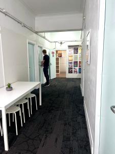 a man standing in a room with a table and chairs at The Downing Hostel in Sydney