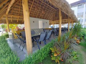 eine Terrasse mit einem Tisch und Stühlen unter einem Strohschirm in der Unterkunft DEPARTAMENTO con alberca in Manzanillo