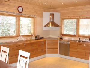 a kitchen with wooden cabinets and a clock on the wall at Villa Tiirinkallio in Nilsiä