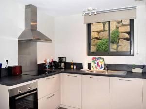 a kitchen with white cabinets and a window at Maison Trégastel, 2 pièces, 4 personnes - FR-1-368-70 in Trégastel