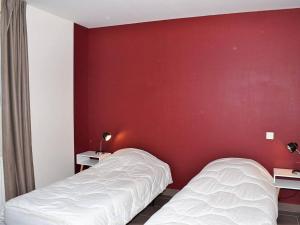 two beds in a room with a red wall at Maison Trégastel, 3 pièces, 4 personnes - FR-1-368-72 in Trégastel