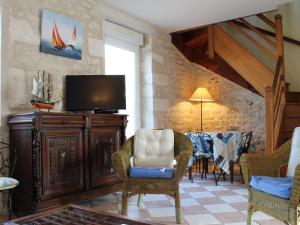 a living room with a tv and chairs at Maison proche centre de St Pierre, 6 couchages, cour ensoleillée, à 20 min de la mer à vélo. - FR-1-246A-83 in Saint-Pierre-dʼOléron