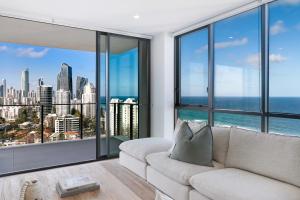 a living room with a white couch and large windows at Opus Broadbeach in Gold Coast