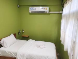a green room with two beds and a air conditioner at Airport one station hometel - Suvarnabhumi - SHA Extra Plus in Bangkok