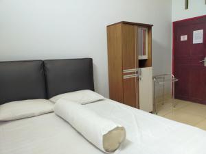 ein Schlafzimmer mit einem weißen Bett mit einem schwarzen Kopfteil in der Unterkunft Inawa Homestay Syariah in Rampal