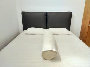 ein Bett mit einem schwarzen Kopfteil und zwei weißen Kissen in der Unterkunft Inawa Homestay Syariah in Rampal + 12 Fotos