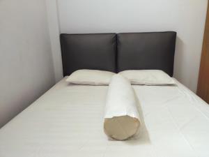 ein Bett mit einem schwarzen Kopfteil und zwei Kissen in der Unterkunft Inawa Homestay Syariah in Rampal