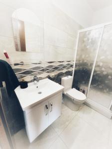 a bathroom with a white sink and a toilet at Amazing seaview studio with pool-steps away beach in Áyios Yeórgios