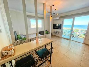 a living room with a table and chairs with a view of the ocean at Amazing seaview studio with pool-steps away beach in Áyios Yeórgios